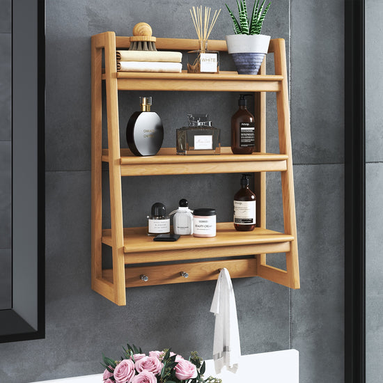 Modern bathroom aira shelf made of teak wood, holding various bottles, a plant, and rolled towels.