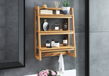 Modern bathroom aira shelf made of teak wood, holding various bottles, a plant, and rolled towels.